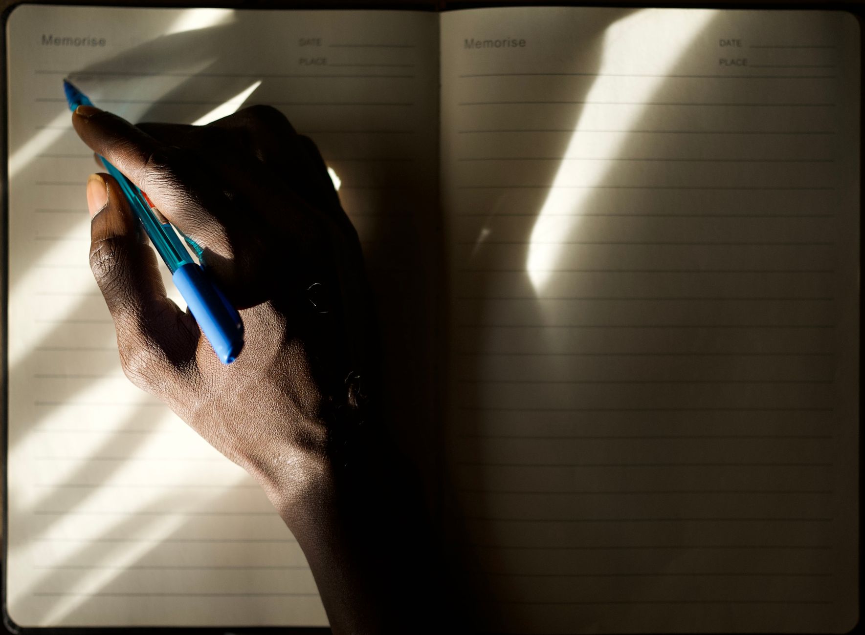 Mains écrivant dans un journal avec jeu de lumière et ombre