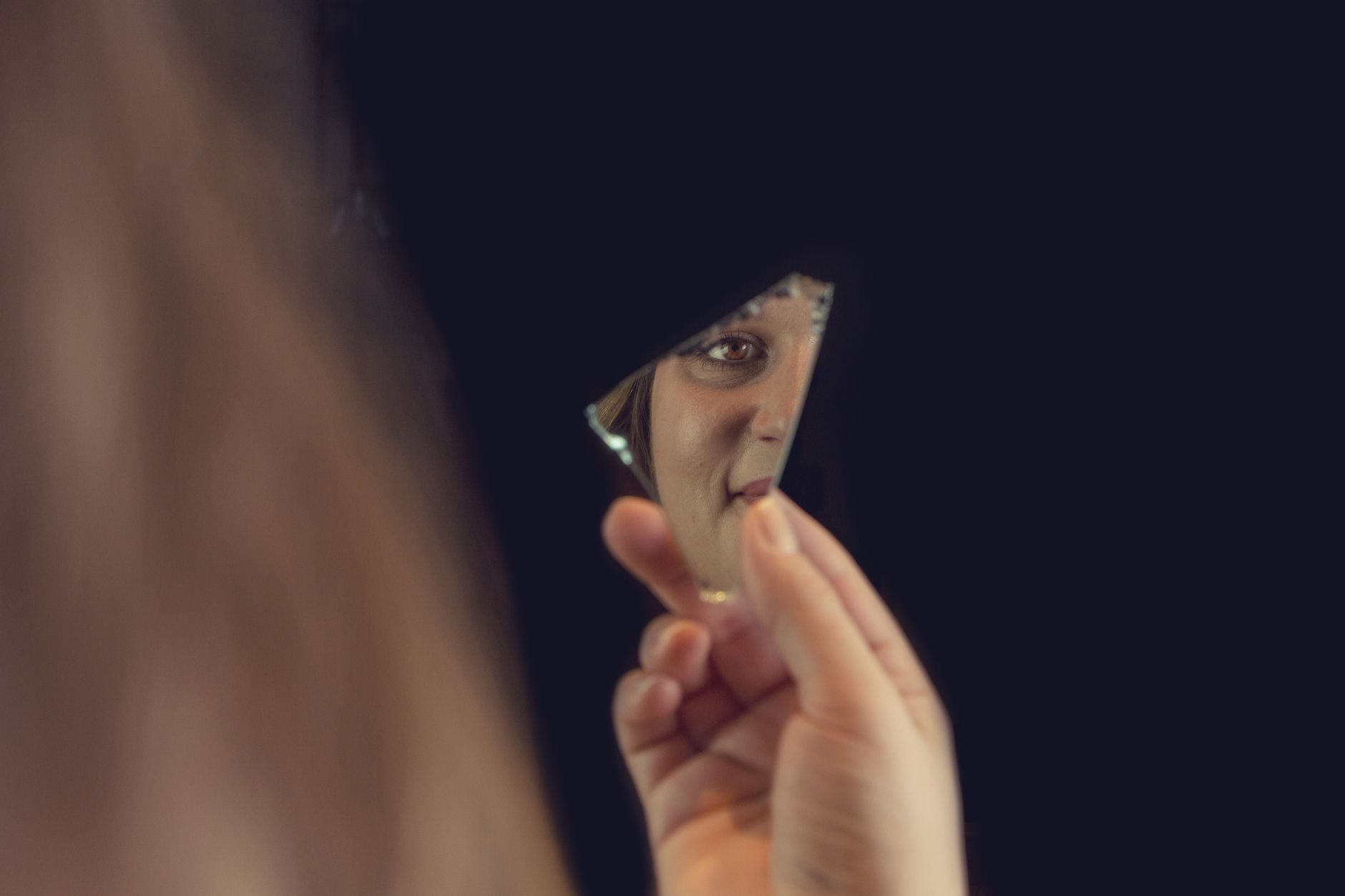 Un reflet fragmenté dans du verre cassé évoquant l'identité dispersée